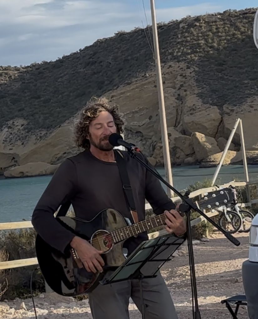 Pat singing by the sea with guitar
